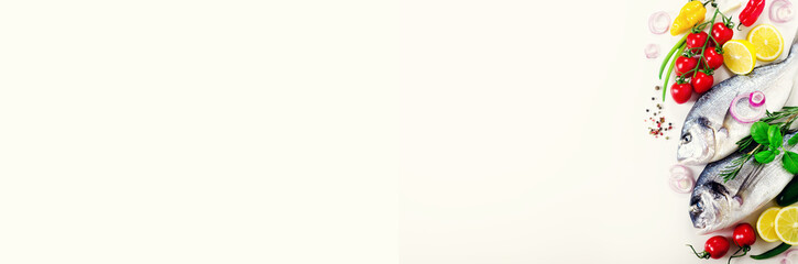 Fresh uncooked fish, dorado, sea bream with lemon, herbs, vegetables and spices on white background. Top view. Banner