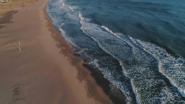 Aerial drone footage like screensaver or background video for text of calm and beautiful crystal clear waters ocean waves crush on sandy empty beach during sunset or sunrise, inspirational destination