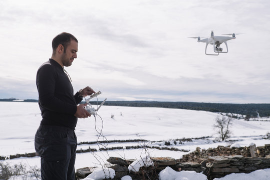 Man flying drone in snowy landscape
