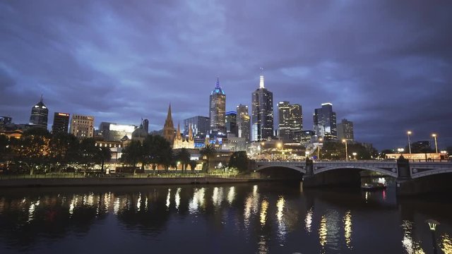 night time wide angle view of a boat on the yarra river with the australian city of melbourne in the background