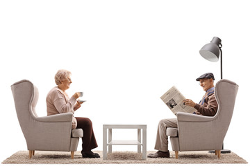 Elderly woman with a cup and an elderly man reading a newspaper