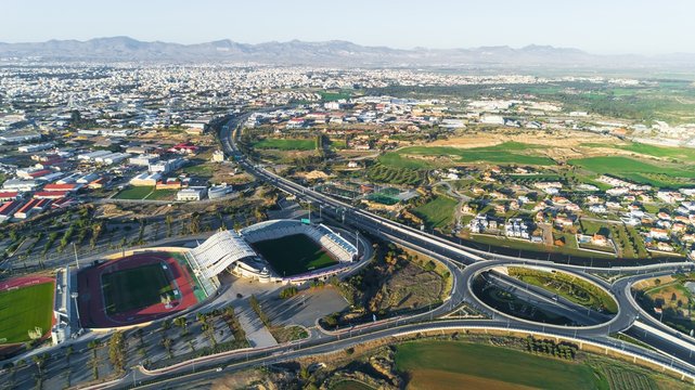 Aerial bird's eye view of GSP football stadium, highway A1 and round about at Latsia, Nicosia, Cyprus. The soccer field, athlete track, seats and auxiliary pitch of national team from above