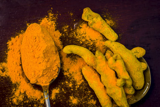 Turmeric,Curcuma longa and its powder on a wooden surface.;