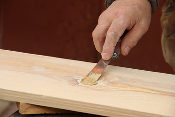 Putty knife in old man's hand. Removing paint from a wood surface. Preparation of boards before...