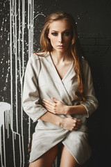 Obraz premium Beautiful fashionable half-naked brown-haired woman in the jacket pose in front of the dark wall