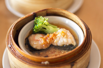 The set of Chinese steamed food in bamboo round flat basket served on the table , the food made from meat such as pork shrimp or fish and can be seen things like these in restaurant. 