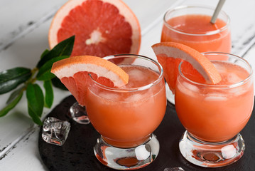 Grapefruit juice and ripe grapefruits on a wooden background