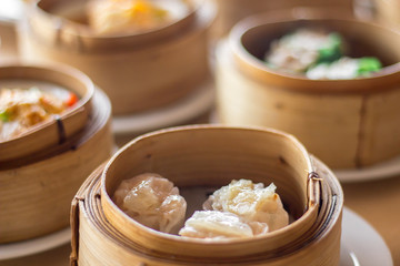 The set of Chinese steamed food in bamboo round flat basket served on the table , the food made from meat such as pork shrimp or fish and can be seen things like these in restaurant. 