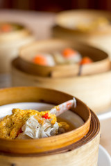 The set of Chinese steamed food in bamboo round flat basket served on the table , the food made from meat such as pork shrimp or fish and can be seen things like these in restaurant. 