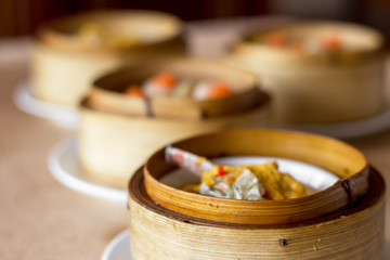 The set of Chinese steamed food in bamboo round flat basket served on the table , the food made from meat such as pork shrimp or fish and can be seen things like these in restaurant. 