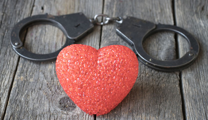 heart in handcuffs on the wooden background