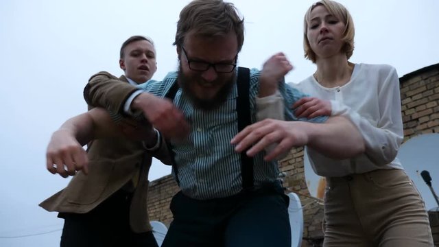 Two young men and a girl kicking a lying person behind the frame, bottom view. 60 fps