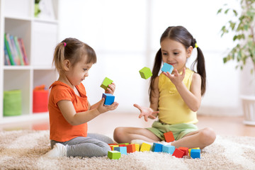 Cute children playing while sitting on carpet at home