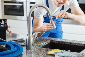 Smiling plumber fixing faucet