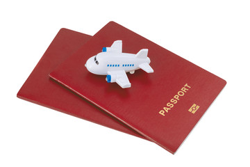 Small toy plane on top of two red passports on a white background.