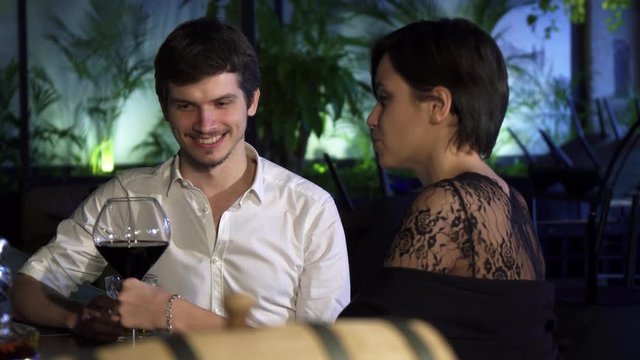 Young couple having romantic date at the bar drinking together and talking