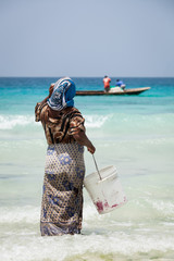 Woman waiting for fishing boat to come into shore in Stone Town, Zanzibar Island, Tanzania.