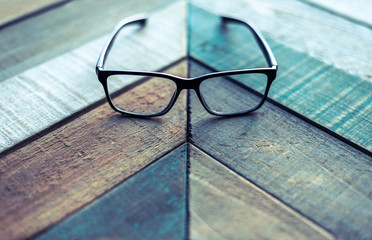 Modern black designer eyeglasses on weathered wood surface with angular pattern. - obrazy, fototapety, plakaty