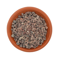 Top view of a small terracotta bowl filled with Himalayan black salt isolated on a white background.