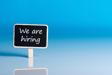 little wooden tag with message We're Hiring. Job offer open new way and give new opportunities