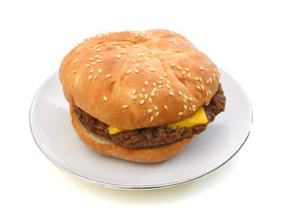 Cheeseburger and Mustard in sesame seeded bun isolated in plate on white from overhead.