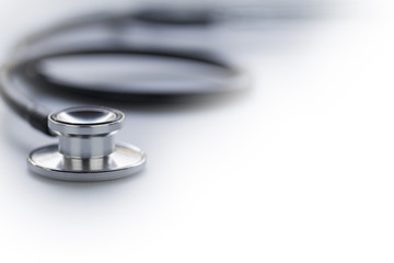 Black stethoscope in shallow depth-of-field isolated on white background with side copy space for text area.