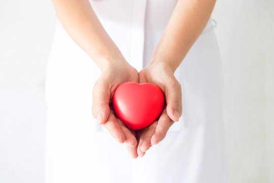 Female nurse holding a red heart shape. Health, Insurance and love concept.