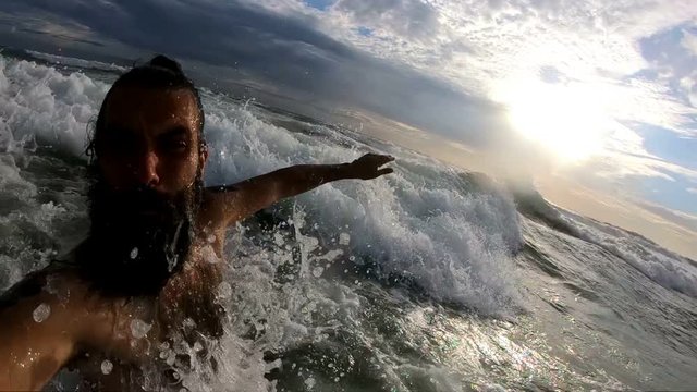 Handsome man filming himself in big ocean waves gopro 240fps slow motion