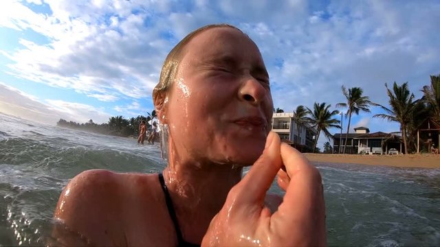 Close up funny girl emerges from under the water sunset gopro 240fps slow motion