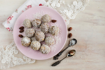 Useful candy made from dates, almonds and coconut on a pink plate
