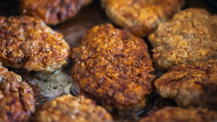 Steaks in a frying pan are roasted on the stove. Fried cutlets