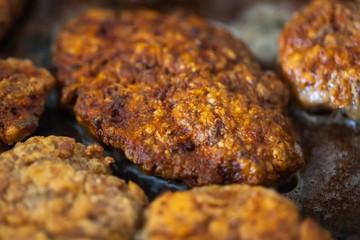Steaks in a frying pan are roasted on the stove. Fried cutlets