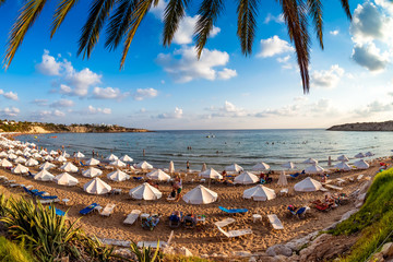 Tourists relaxing on the beach in the summer vacation. Peyia village, Paphos District, Cyprus