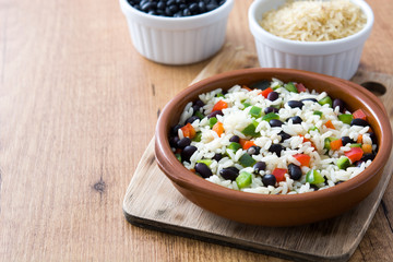 Traditional cuban rice, black beans and pepper on wooden table background. Moros y cristianos.