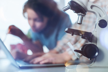 Special equipment. Two motivated dynamic inspired kids sitting in school lab while studying biology and developing their scientific project
