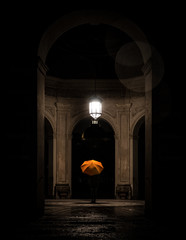 Young Woman with orange umbrella standing in a temple in the dark in Hofgarten Munich by night //...