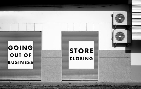 Large printed signs in a department store window announcing store closing and price reductions.
store closing