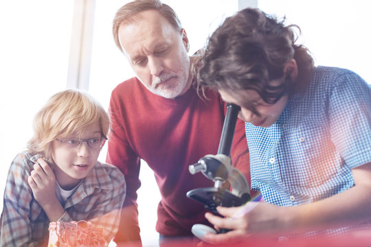 Scientific mentor. Nice attentive awesome professor guiding young boys who being enthusiastic about biology and studying bacteria in lab