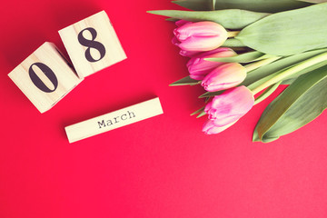 8 March Happy Women's Day concept. With wooden block calendar and pink tulips on red background