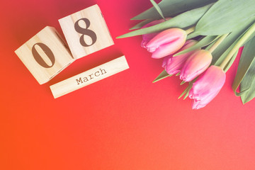 8 March Happy Women's Day concept. With wooden block calendar and pink tulips on red background