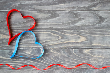 Valentine's Day . Two hearts of ribbons of red and blue on a background of wood.