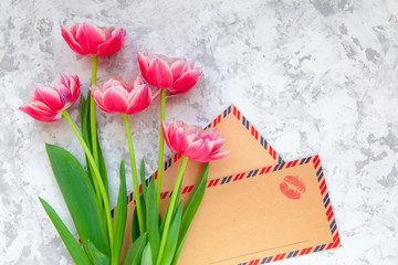 Pink tulips and vintage kraft envelopes with kiss print on light textured background. Happy valentine's day concept.