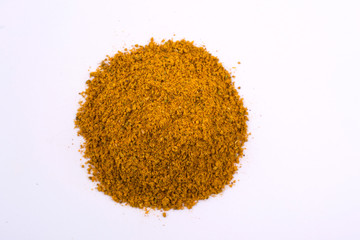 A pile of a yellow spice mix for kari  . Isolated on white background. Spices consist coriander turmeric ginger pepper black red cinnamon bay leaf