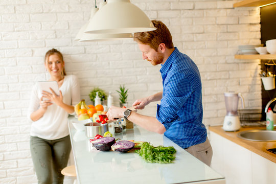 Young couple have fun in modern kitchen indoor while preparing vegetables food for lunch