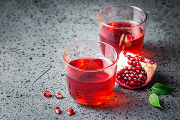 Pomegranate juice in glasses on dark concrete background. Selective focus,space for text.