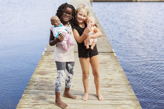 Girls with baby dolls on pier