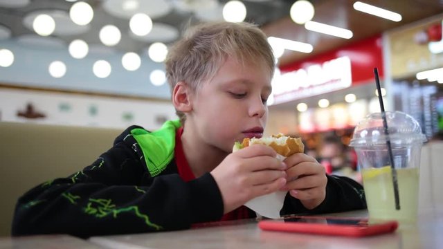 Child eating hamburger at fast food restaurant.