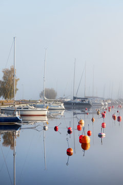 Row of moored sailboats reflecting in water surface