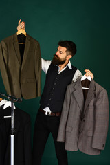 Fashion choice concept. Designer makes choice holding clothes hangers.