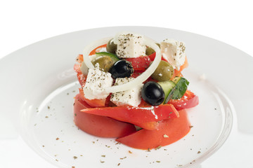 salad of fresh tomatoes, olives, sweet pepper and feta cheese on a white plate, Greek salad